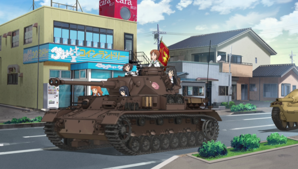 The city of Ōarai, Ibaraki Prefecture in 2013 and as imagined by the animators of Girls and Panzer. Anime-style illustrated image of the photograph of Ekimae Street. There are women riding tanks in the foreground.