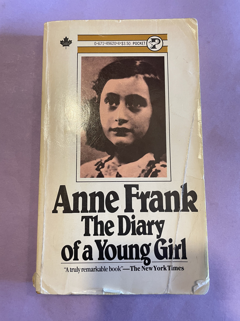 Book cover of Diary of a Young Girl on a purple background. The book is visibly well used. 