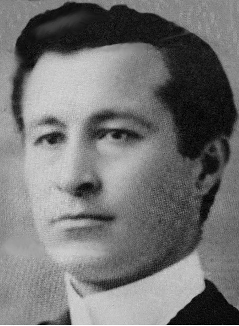 An early-1900 headshot photograph of a young man, Ewen McDonald, wearing a clerical collar.