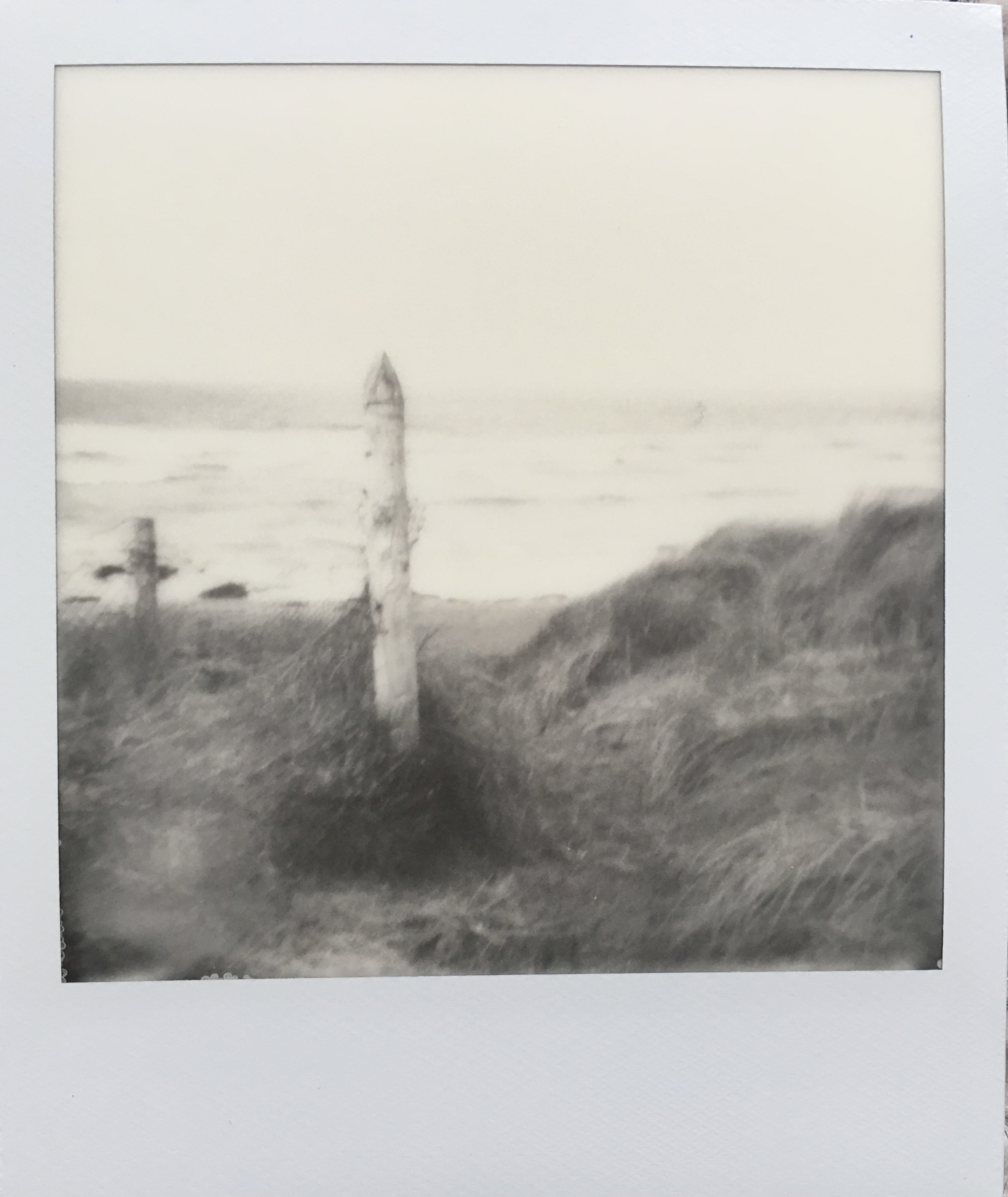 An old pier post rises from the grassy dunes and the soft lines of the tide.