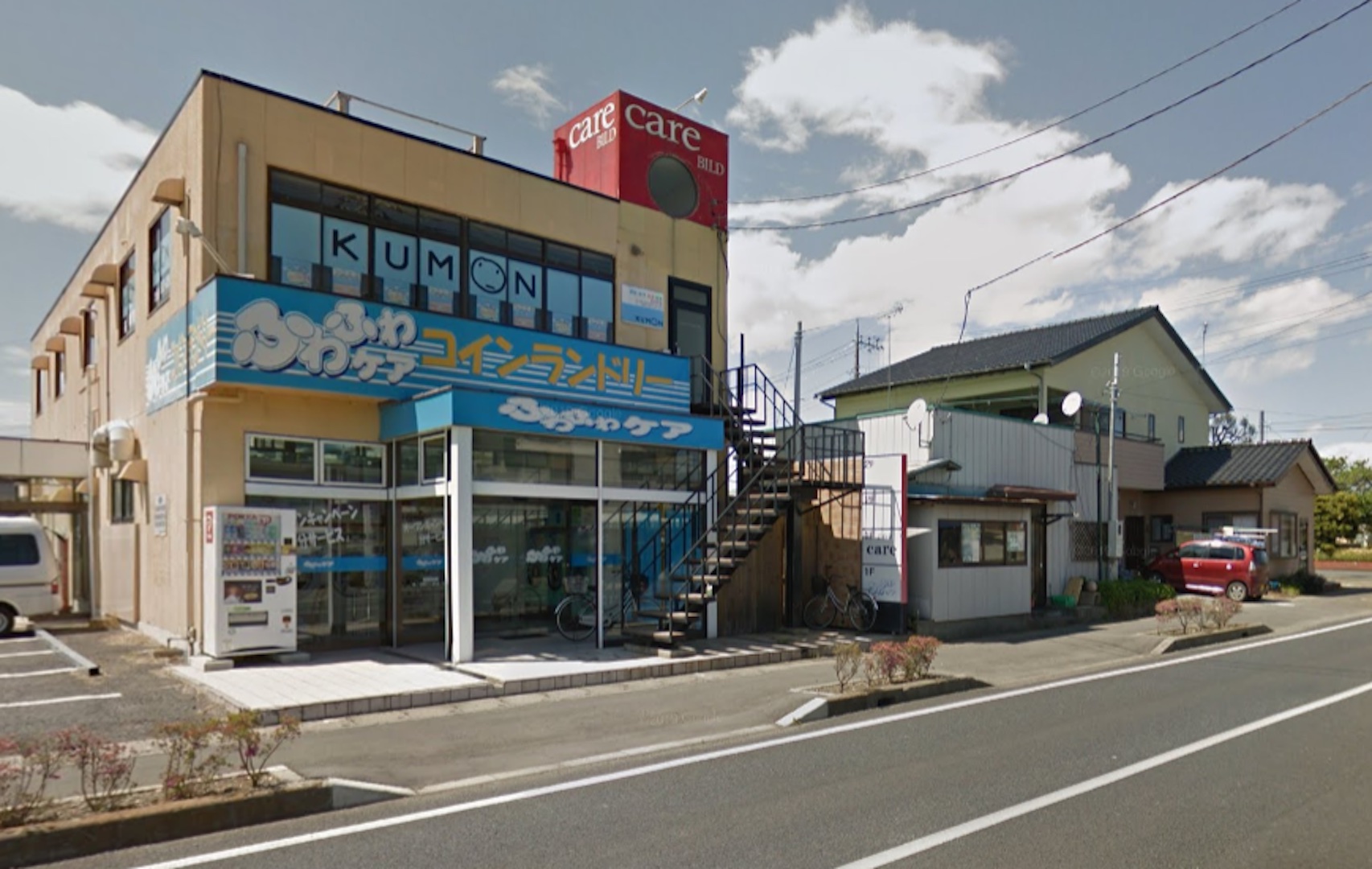 Google Maps, Ōarai, Ekimae Street, May 2013 Photograph of Oarai, Ekimae Street, in 2013. A building with blue-and-yellow signage is situated across a street. There are other buildings to the left of it.