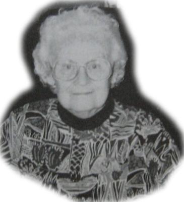 Black and white photo of an older woman wearing round glasses and a patterned sweater.