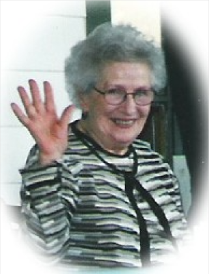 Ruth Macdonald A woman wearing a striped cardigan is smiling and waving at the camera.