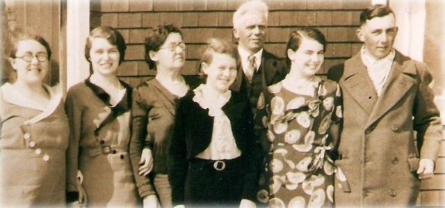 Sepia tinted photo of seven people standing outdoors.