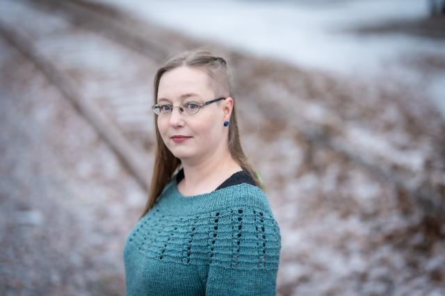 Kaisa Ranta Woman with long light-coloured hair wearing glasses and a green sweater.