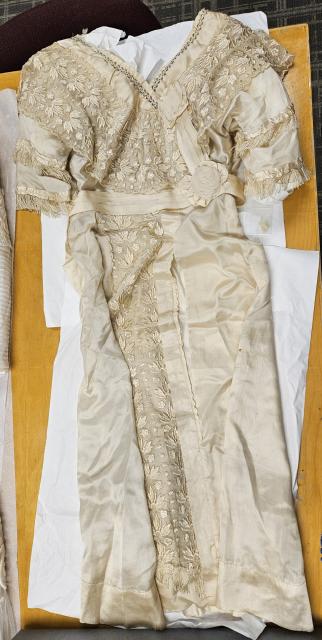 Unknown wedding gown Ivory silk and lace wedding gown detailed with tasselled short sleeves, fabric rosettes, pleated waistband, and steel-cut beading at the neckline.