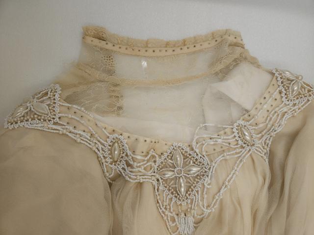 Gown front beading Montgomery’s original gown’s bodice showing steel-cut, iridescent ivory, and white beading, archived at the Confederation Centre of the Arts, Charlottetown, PEI.