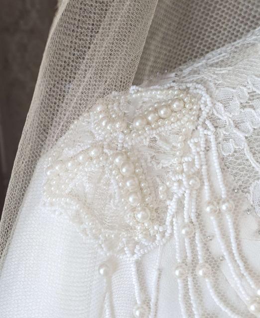 Replica gown shoulder beading The beaded medallion on the replica wedding gown’s shoulder shown through the original veil at the Lucy Maud Montgomery Birthplace, New London, PEI.