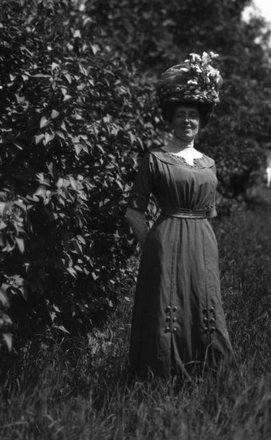 Montgomery modelling wedding trousseau Montgomery modelling an elaborate Edwardian hat and brown poplin dress with button detailing, lace inset sleeves and collar, and front pleats.