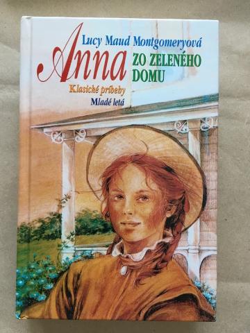 Anna zo Zeleného domu 2002 Colourful, smiling Anne wearing a brown dress and a hat. Behind her are a porch and some wildflowers.