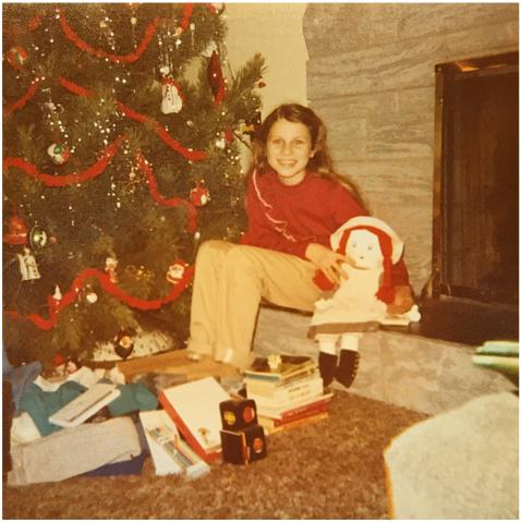 Hope Dalvay A child sits in front of a Christmas tree near an indoor fireplace.
