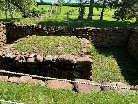 Photo of stone foundation of house surrounded by greenery.
