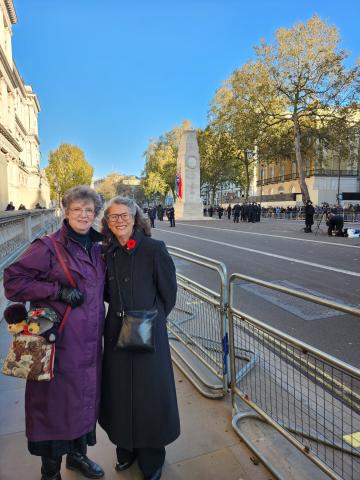 Andrea McKenzie Andrea and her sister Allison Dean stand side-by-side, smiling at the camera, with the Cenotaph in the background Andrea wears a long, grey coat with and Allison wears a long maroon coat.