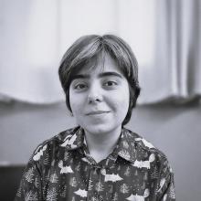 Mina Mollaie black-and-white photo of a person with short hair wearing a patterned button-up shirt